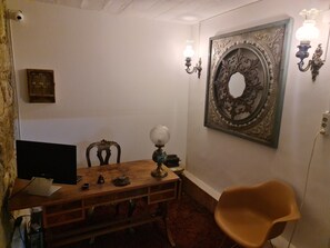 Un coin repas comprenant une table en bois, une chaise moderne, un téléviseur à écran plat et des appliques murales décoratives.