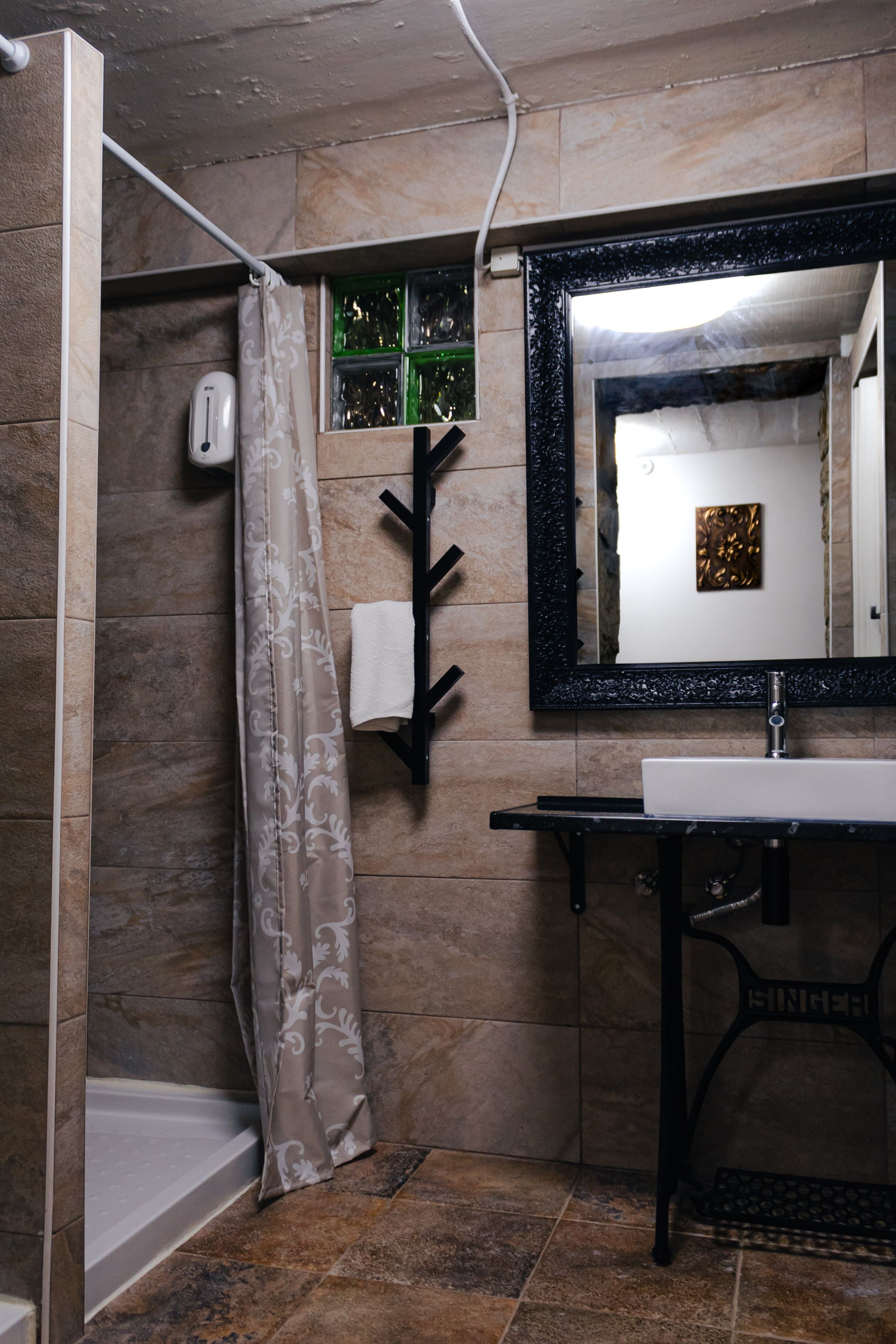 A bathroom with a shower, a sink, a mirror, and a towel rack.