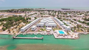 An aerial view of a resort with multiple buildings, a dock with boats, and a swimming pool. - Ocean Isles #98~ Fishing Village, Community Pool! (Marathon)
