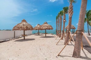 A beach with thatched umbrellas, palm trees, and a clear view of the sea. - Ocean Isles #98~ Fishing Village, Community Pool! (Marathon)