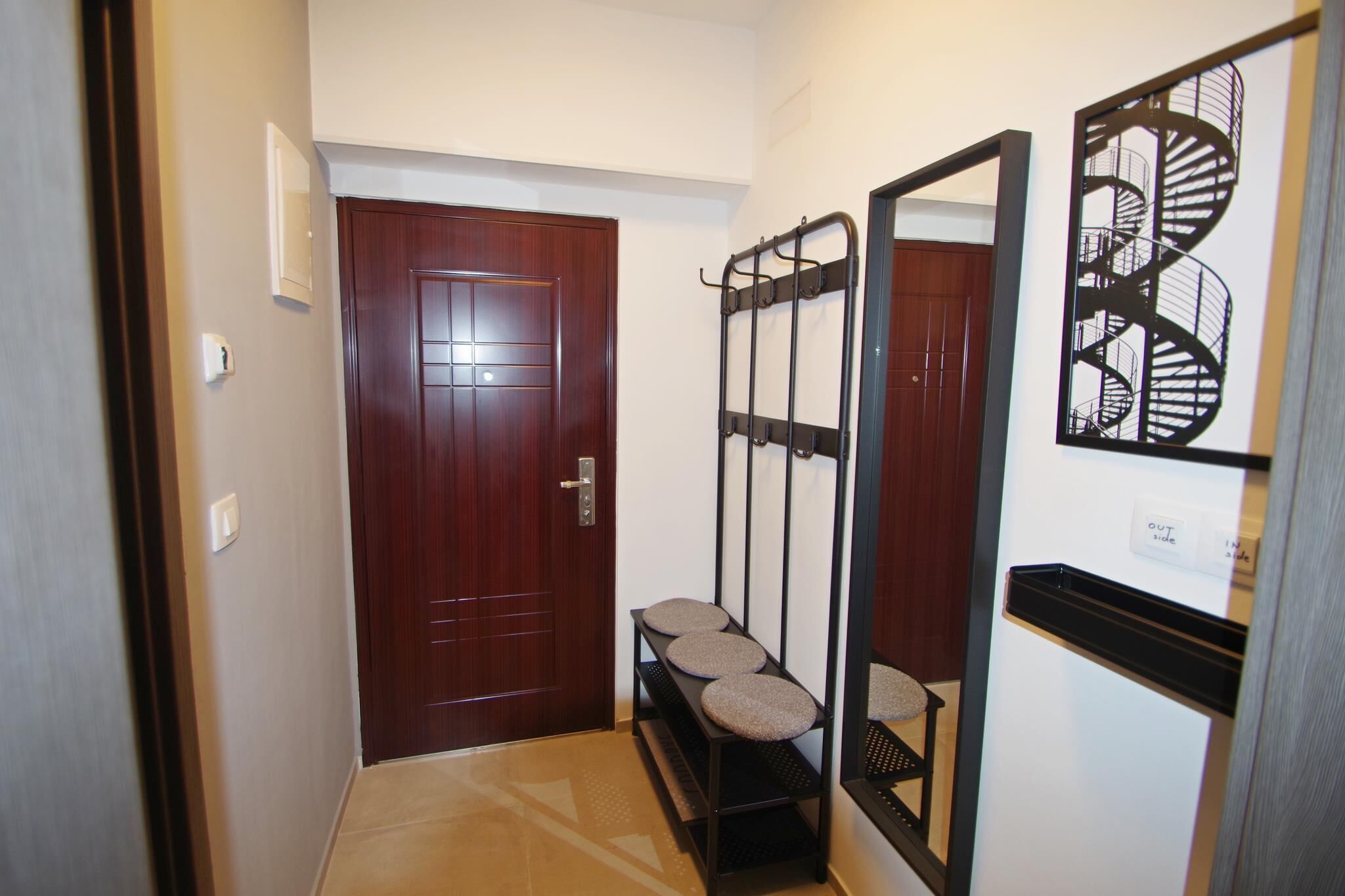 A hallway with a wooden door, a bench, and a wall-mounted rack.