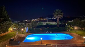 Ein Schwimmbecken bei Nacht mit Blick auf eine an einem Hügel liegende Stadt.