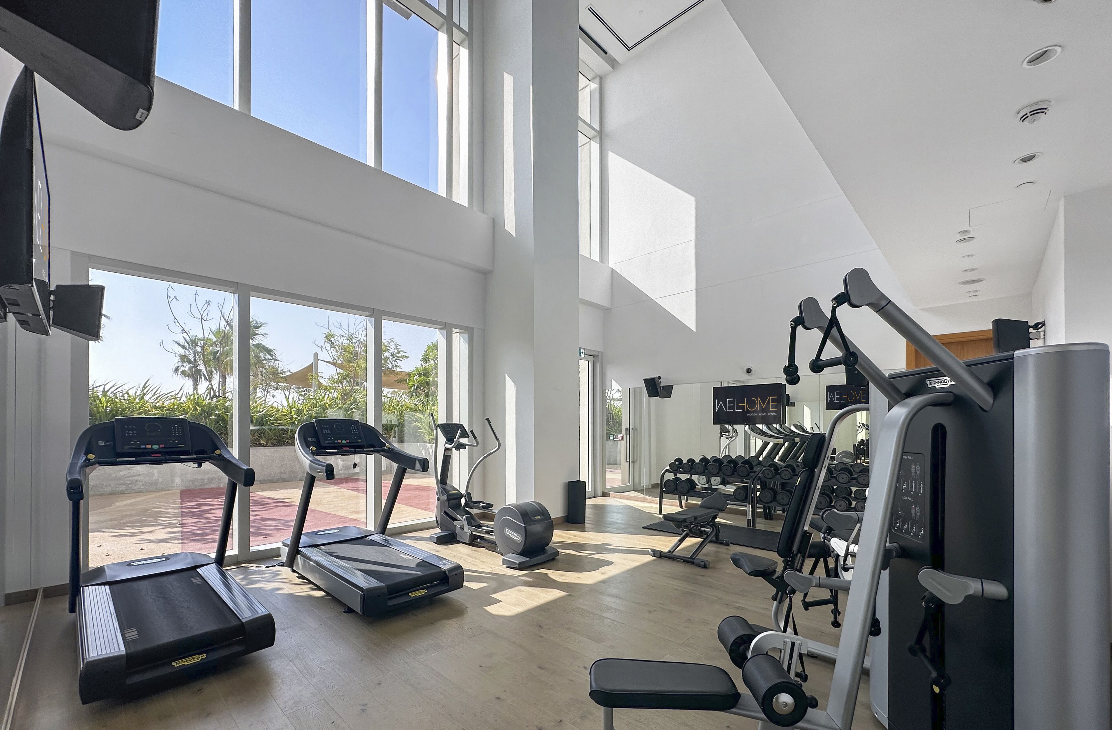 Ein geräumiges Fitnessstudio mit Laufbändern, Crosstrainern und Gewichten.