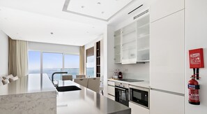 Experience the perfect blend of functionality and comfort in this stylish hotel room, featuring a spacious kitchen area, central island, and expansive city views.