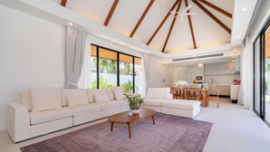 A modern living room with a sofa, coffee table, and a view of the kitchen. -  Anchan Villas Phuket - Private 4 Bedroom Signature Pool Villa by Escape Villas (Choeng Thale)