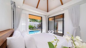 A modern bedroom with a large bed, white linens, a view of a swimming pool, and a sliding glass door leading to an outdoor area. -  Anchan Villas Phuket - Private 4 Bedroom Signature Pool Villa by Escape Villas (Choeng Thale)