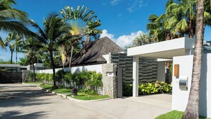 A modern house with a stone entrance, a covered patio, and a well-maintained garden with palm trees. -  Anchan Villas Phuket - Private 4 Bedroom Signature Pool Villa by Escape Villas (Choeng Thale)