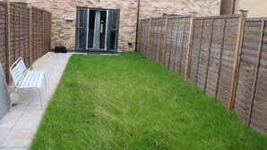 A small, fenced backyard with a grassy area and a bench. - Family Home 5-bed House in Birmingham City Centre (Birmingham)