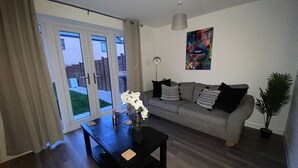 A modern living room with a grey sofa, a black coffee table, and a potted plant. - Family Home 5-bed House in Birmingham City Centre (Birmingham)