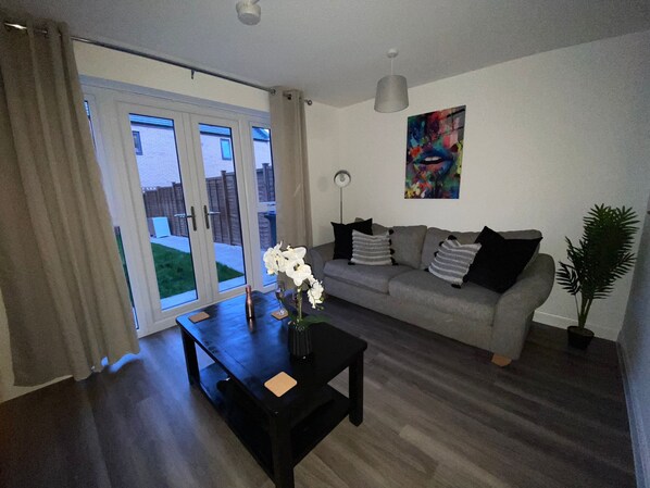 A modern living room with a grey sofa, a black coffee table, and a potted plant.