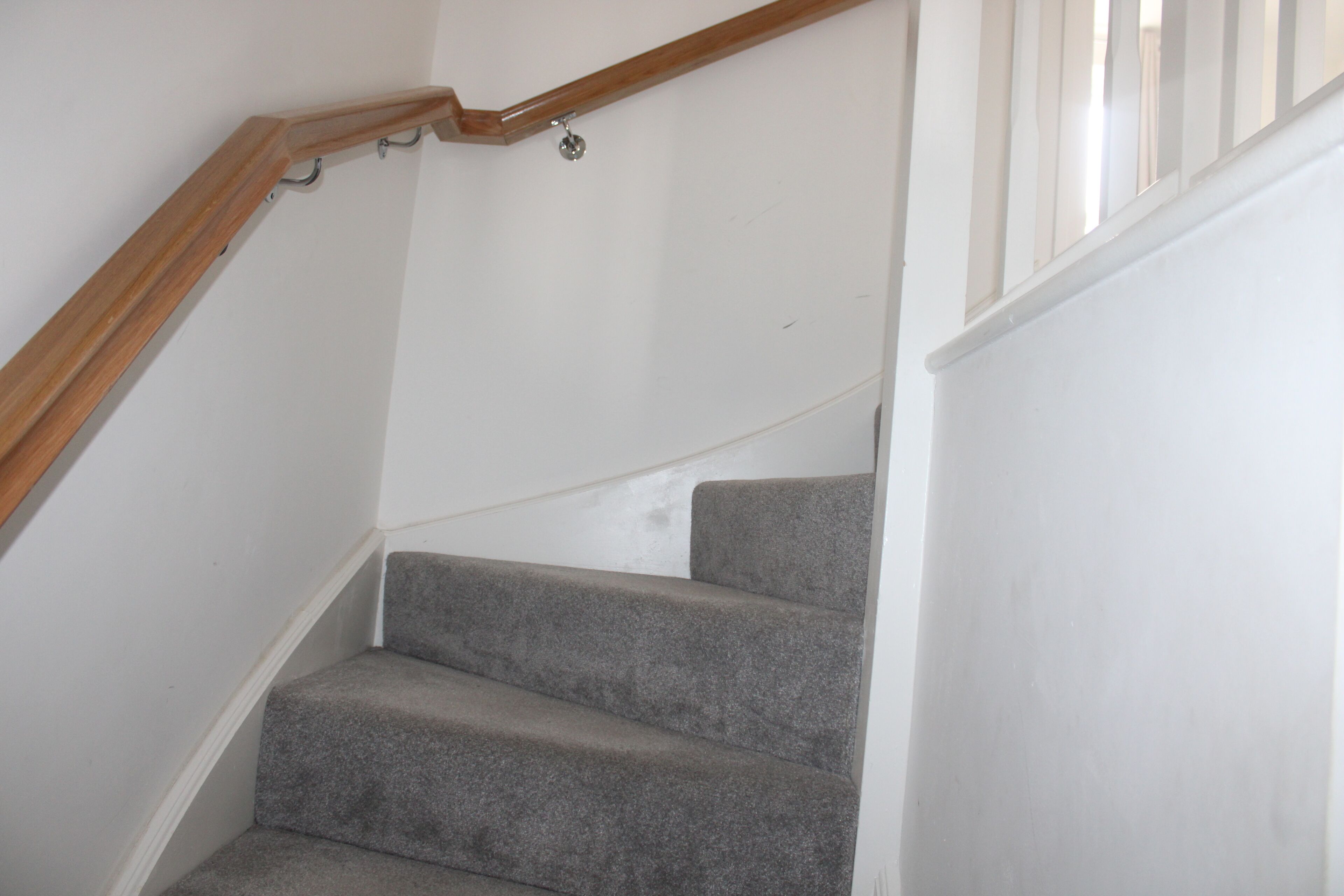 Eine Treppe mit Holzbalkon und Teppichstufen.