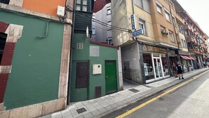 A street view with a green building, a yellow building with a sign for 'Llanogr', and a brown building with balconies. - Yani's hospedaje (Parres)