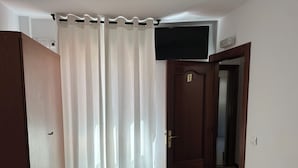 A room with a wooden door, a white curtain, and a flat-screen TV mounted on the wall. - Yani's hospedaje (Parres)