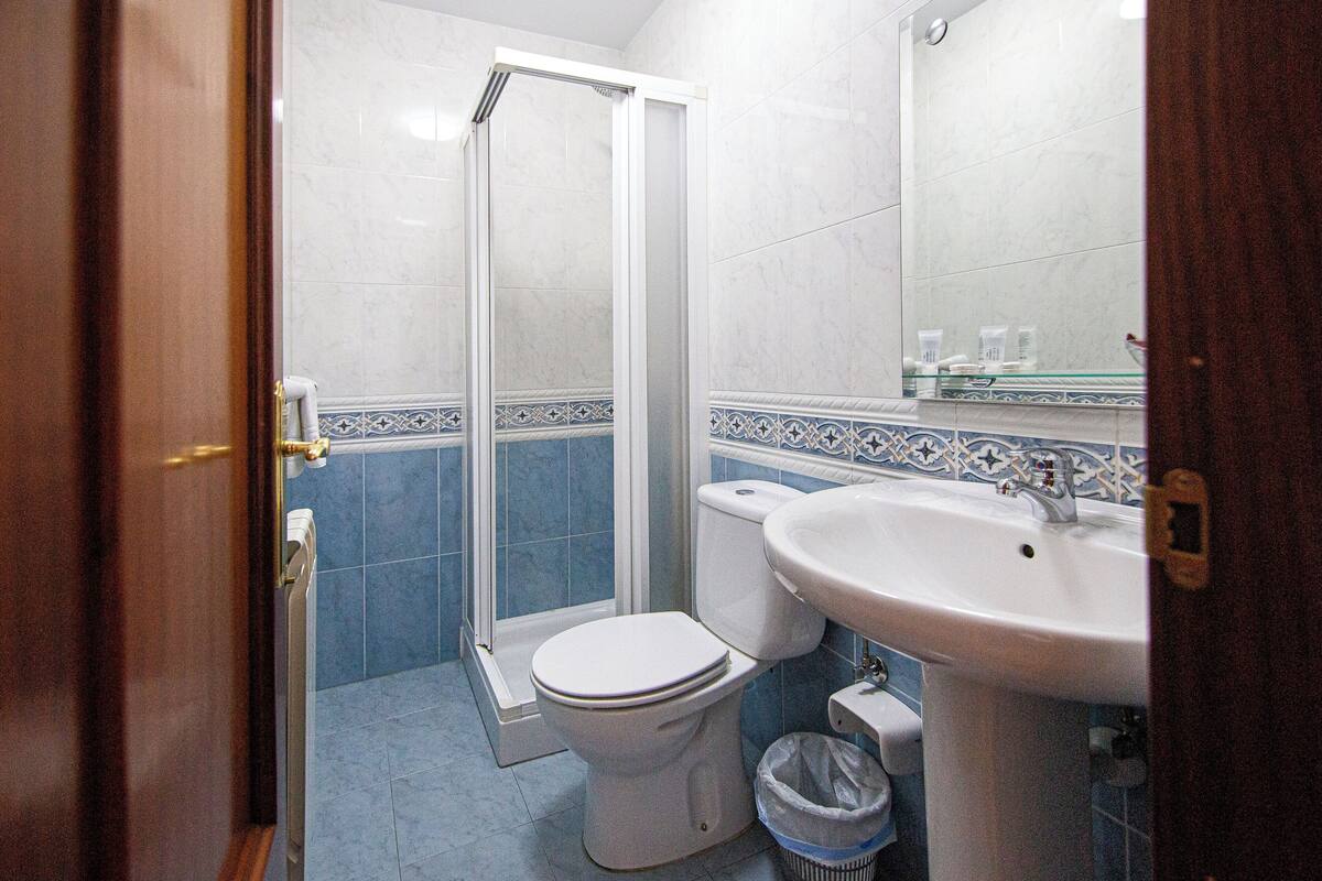 Un baño con inodoro, lavamanos y cabina de ducha de vidrio.