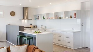 A modern kitchen with a central island, bar stools, and a built-in oven.
