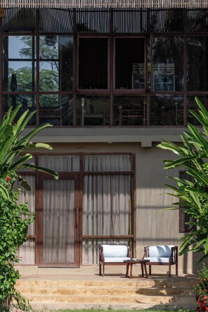 A two-story building with large windows, a balcony, and a seating area with a table and chairs.