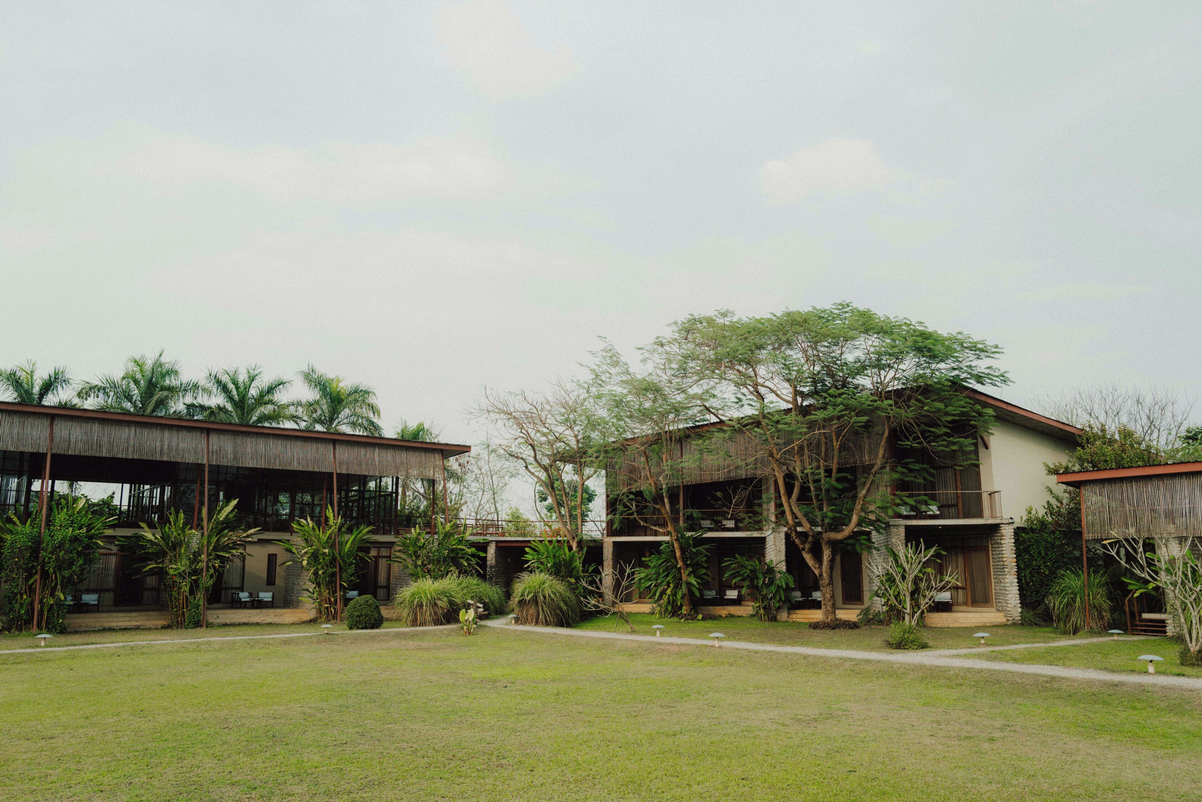 A building with a covered outdoor area, surrounded by grass and trees.