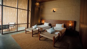 Un dormitorio moderno con dos camas, un ventanal grande y vistas al exterior.