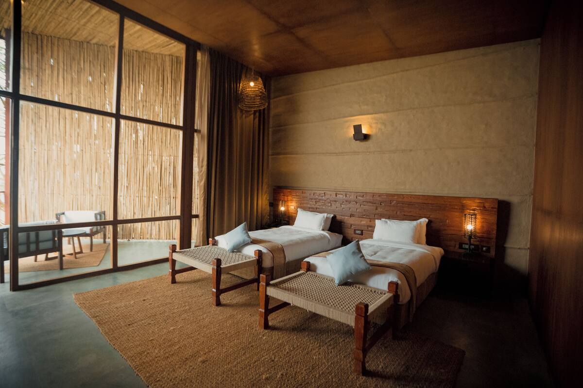 A modern bedroom with two beds, a large window, and a view of the outdoors.