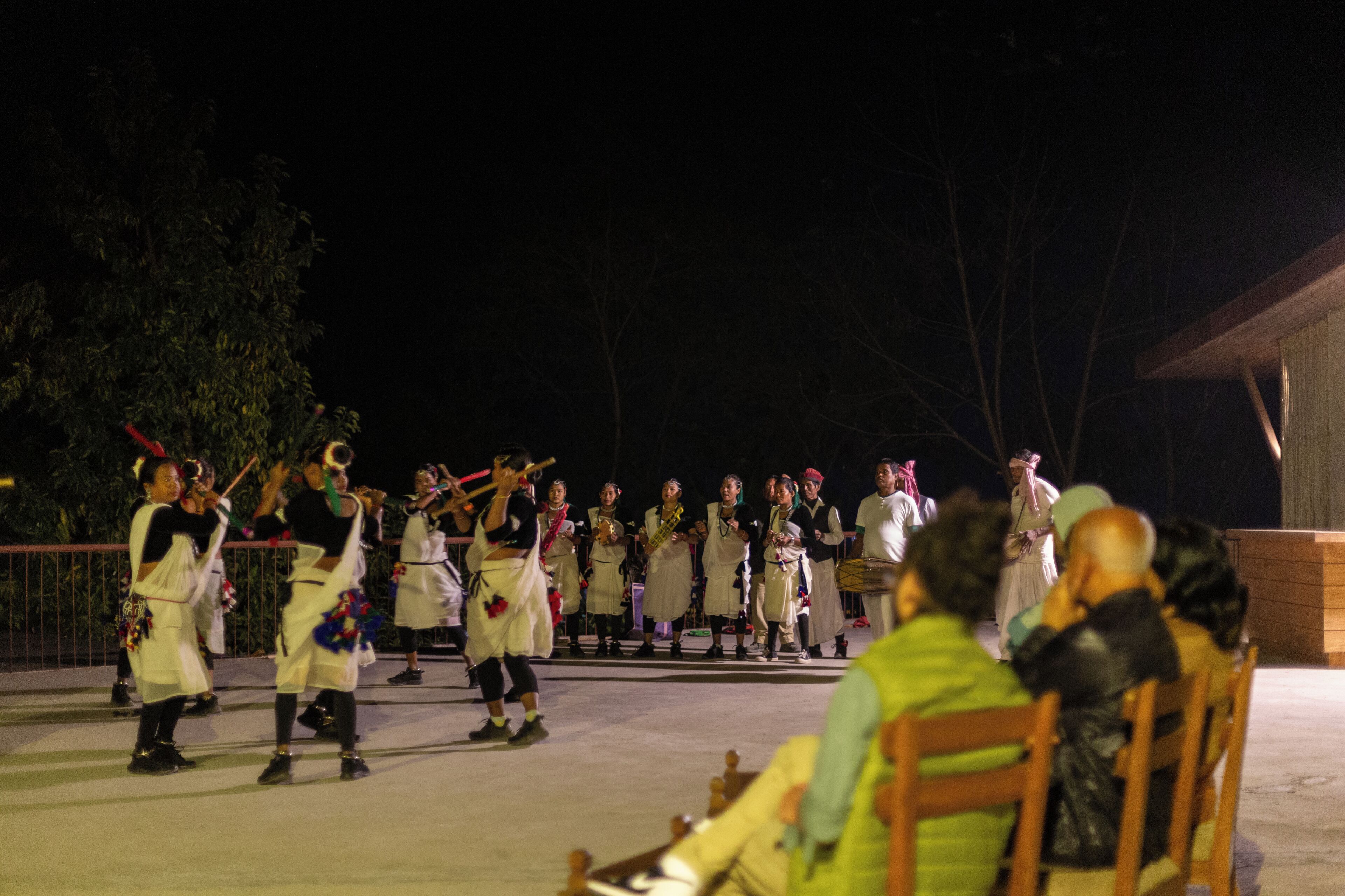 A group of people in traditional attire performing on a stage at night.