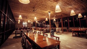 Un restaurante espacioso con mesas de madera y lámparas de mimbre colgantes.