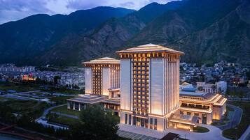 A hotel with a central courtyard, surrounded by a cityscape and mountains.