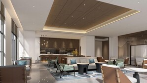 A spacious lounge area with a modern kitchen in the background, a seating area with sofas and tables, and a high ceiling with recessed lighting. - Courtyard By Marriott Jiuzhaigou (Ngawa Autonomous Prefecture)