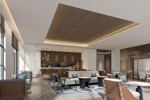 A spacious lounge area with a modern kitchen in the background, a seating area with sofas and tables, and a high ceiling with recessed lighting. - Courtyard By Marriott Jiuzhaigou (Ngawa Autonomous Prefecture)