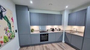 A modern kitchen with grey cabinets, a built-in oven, and a sink. - 4 Bed Townhouse | Free Parking | Piccadilly (Greater Manchester)