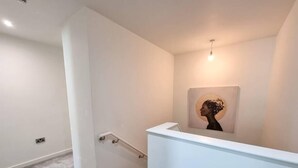 A modern interior with a white wall, a framed artwork, and a carpeted floor. - 4 Bed Townhouse | Free Parking | Piccadilly (Greater Manchester)