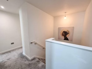 A modern interior with a white wall, a framed artwork, and a carpeted floor.