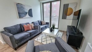 Ein modernes Wohnzimmer mit einem grauen Sofa, einem Couchtisch und einer TV-Konsole.