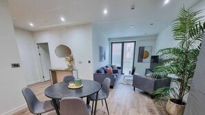 Ein modernes Wohnzimmer mit Essbereich, grauen Sofas, einer großen Kühlpflanze und Blick ins Freie.