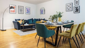 Ein modernes Wohnzimmer mit einer Couch, einem Esstisch, Stühlen und Kunstwerken an den Wänden.