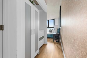 Un couloir menant à une chambre à coucher équipée d’un lit, d’un bureau et d’une fenêtre.