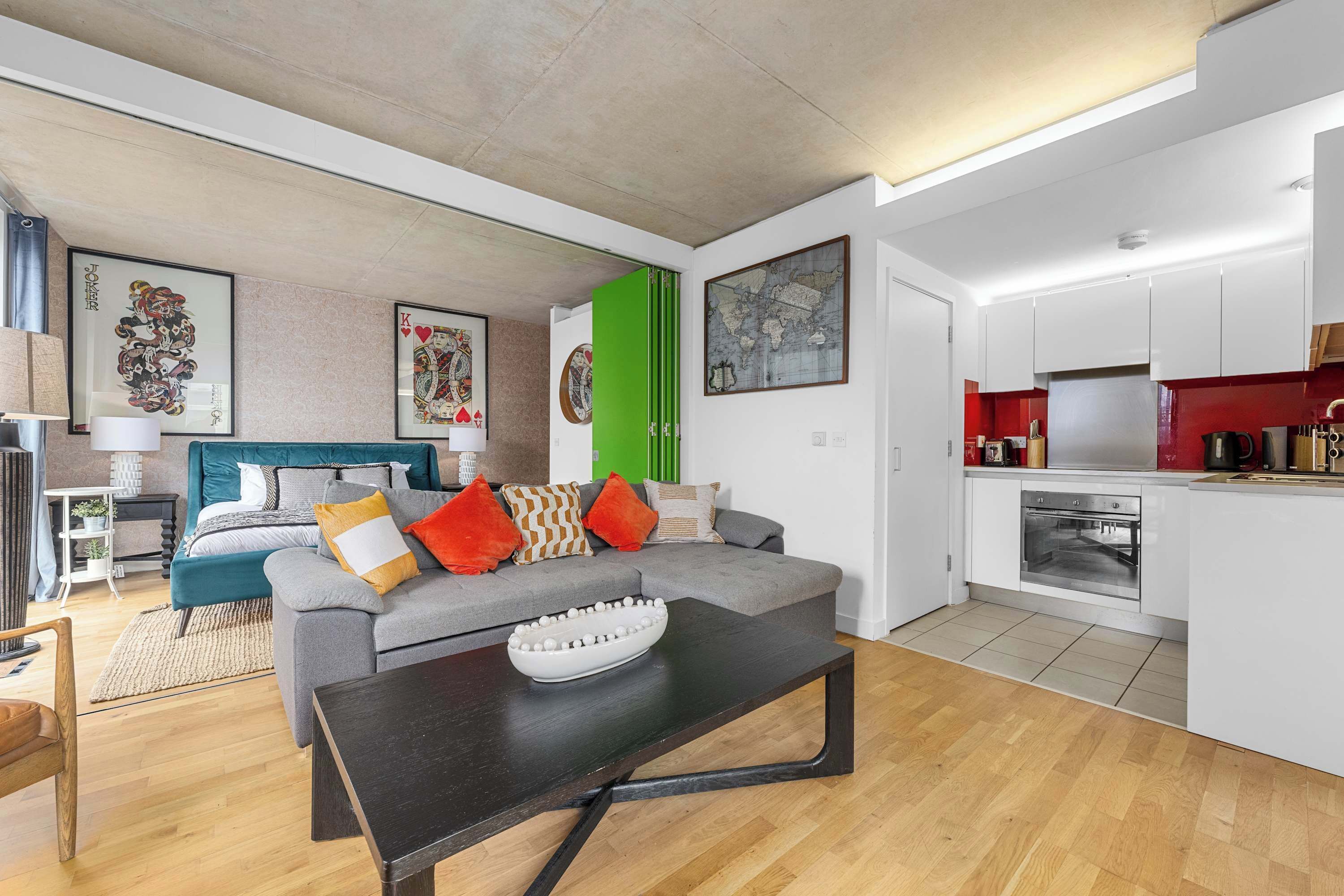 A modern living room with a grey sofa, a black coffee table, and a green door.