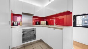 Eine moderne Küche mit weißen Schränken, einem Einbauofen und einer roten Spritzschutzwand.