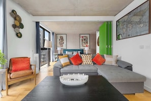 A modern living room with a grey sectional sofa, a wooden chair, and a black coffee table.