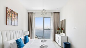 Moderni hotellihuone, jossa on suuri sänky, työpöytä ja näköala merelle.