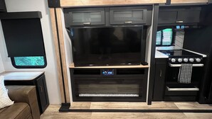 Una cocina compacta con horno integrado, un microondas y un televisor de pantalla plana grande.