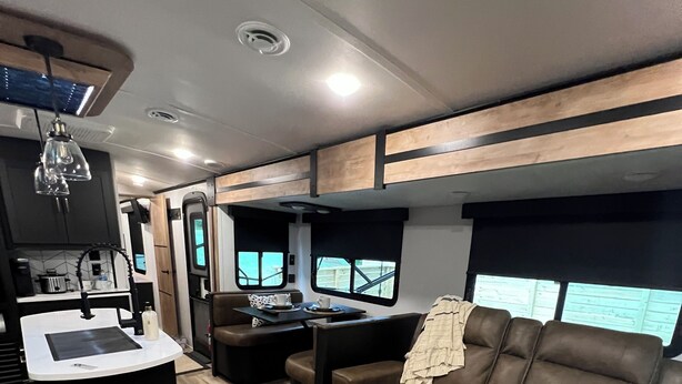 Interior de una caravana compacta con kitchenette, zona de estar y ventanas.