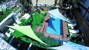 A rooftop pool with a blue water feature, surrounded by white lounge chairs and a green canopy. - Narong Ek Residence View & Pool Villa (Patong)