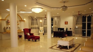 A spacious lobby with a polished floor, a red armchair, a white sofa, and a chandelier. - Narong Ek Residence View & Pool Villa (Patong)