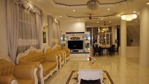 A spacious living room with a large sofa set, a TV, and a dining area with chairs and a table. - Narong Ek Residence View & Pool Villa (Patong)
