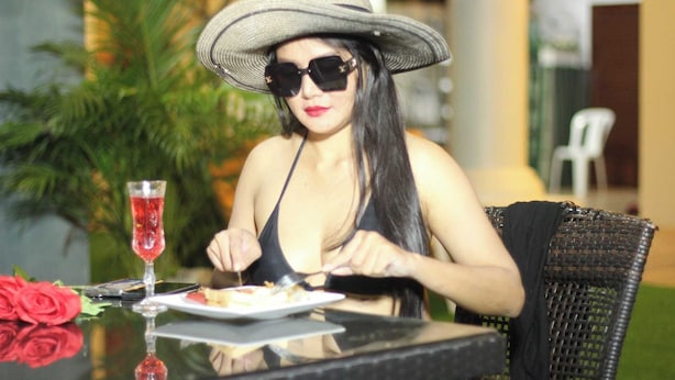 A person dining at an outdoor table with a plate of food, a glass of red beverage, and a rose. - Narong Ek Residence View & Pool Villa (Patong)