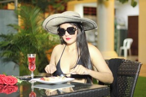 A person dining at an outdoor table with a plate of food, a glass of red beverage, and a rose. - Narong Ek Residence View & Pool Villa (Patong)