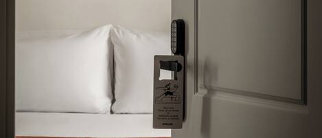 Una habitación de hotel con una cama, un control remoto y una puerta con el símbolo del número.