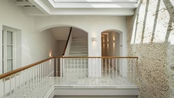 A modern interior with a staircase leading to a mezzanine, white walls, and a textured stone wall.