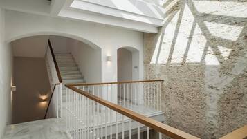 A modern staircase with white railings and wooden handrails, leading to a landing with a skylight.