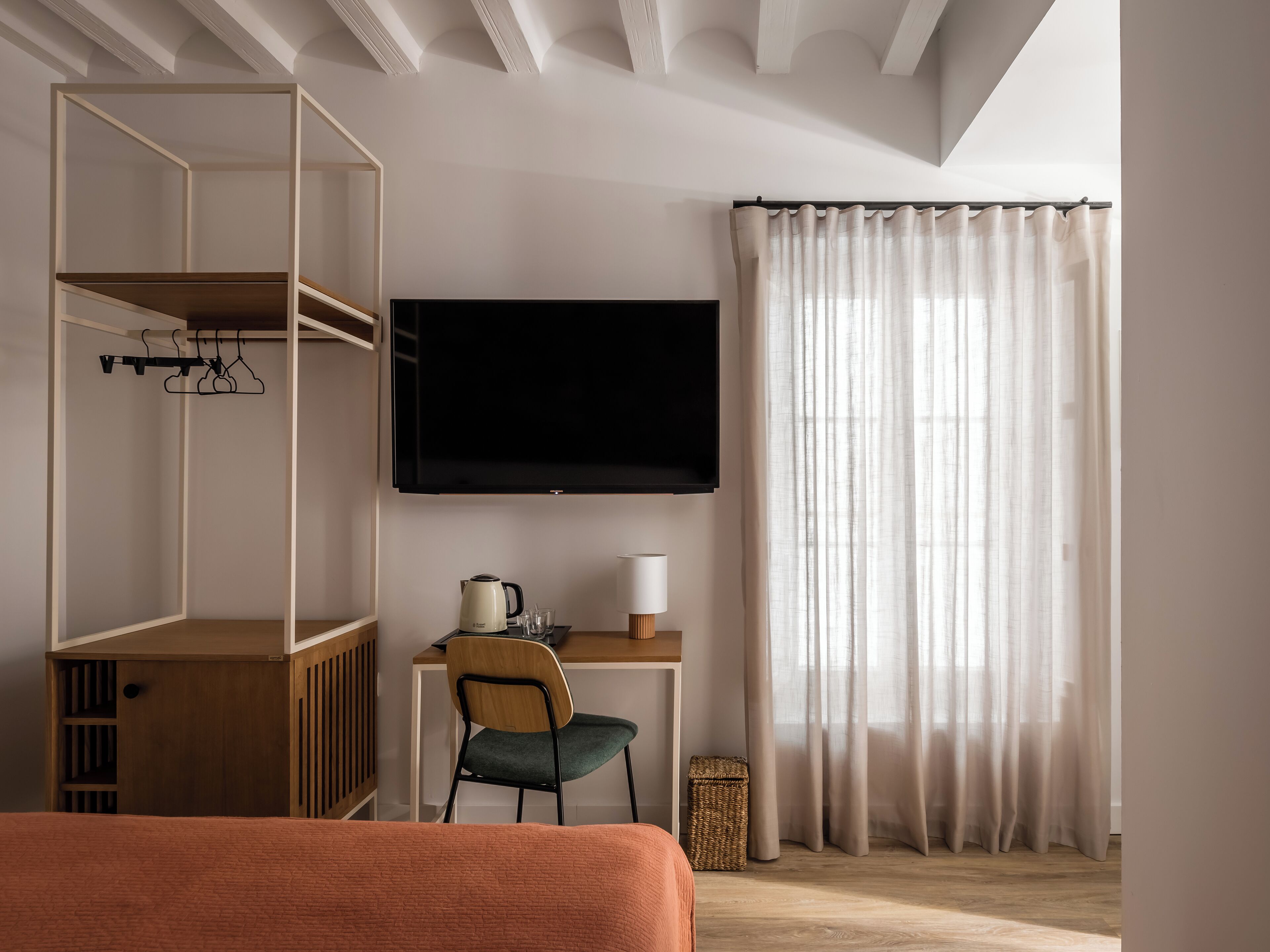 Una habitación moderna con cama, escritorio con silla, televisor y armario.